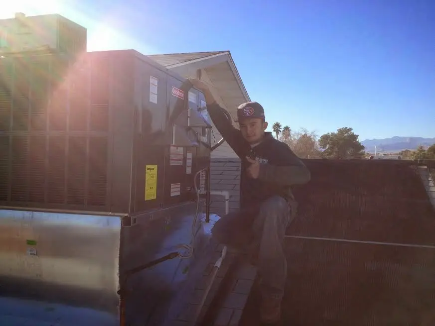 HVAC technician performing AC Tune-Up on a rooftop unit in Milford